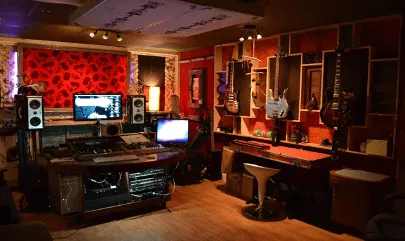 Recording studio with professional audio equipment, guitars on the wall, mixing console, and comfortable acoustic treatment f