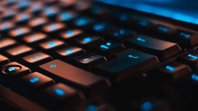 Keyboard with illuminated blue keys, gaming or office setup, technology and digital workspace, vibrant LED lighting, close-up