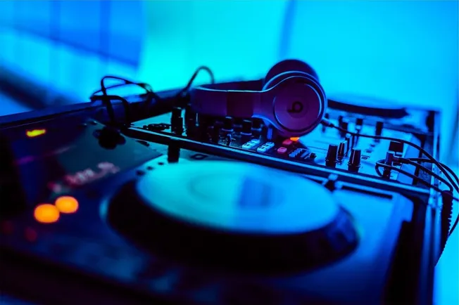 High-quality DJ turntable and headphones setup with vibrant blue and purple lighting, ideal for music industry and electronic