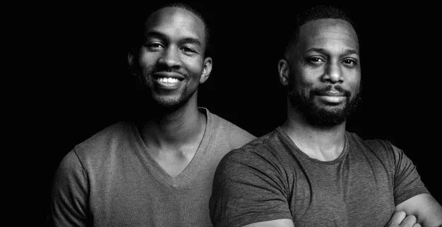 Two men smiling and posing for a portrait in a professional setting, emphasizing diversity and collaboration in the music and
