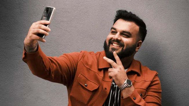 People taking selfies, smiling man with smartphone, casual fashion, urban background, modern technology, social media, influe