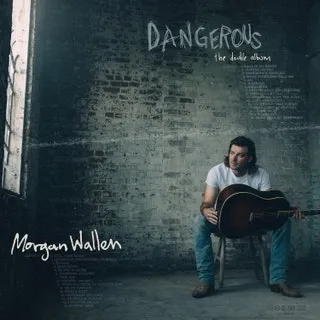 Moody artist portrait of Morgan Wallen with guitar against gritty brick wall, promotional music album cover for Dangerous, co