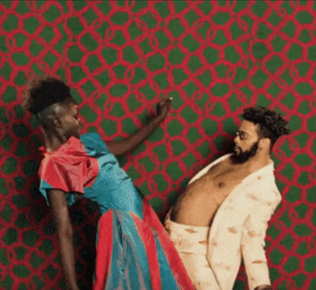 Fashionable couple lying on colorful patterned carpet, vibrant modern attire, artistic portrait, creative fashion photography