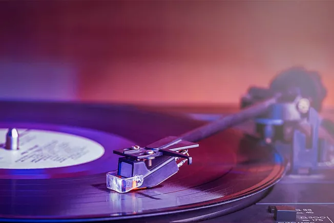 Vintage turntable playing vinyl record with colorful ambient lighting, music industry technology, DJ equipment, and audio mix