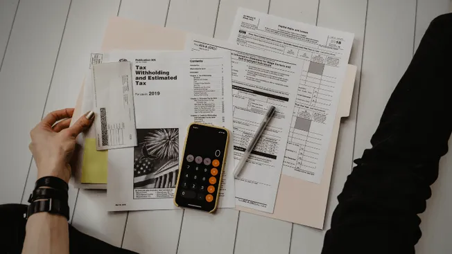 Tax documents, calculator, and financial papers on a desk representing tax preparation, accounting, and financial management.