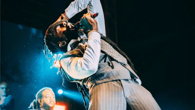 Hip-hop artist performing live on stage with microphone, dynamic concert scene, colorful stage lighting, urban music, energet