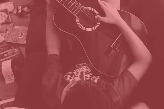 Acoustic guitar player practicing music at home, surrounded by music books and supplies, creating a cozy and artistic musical