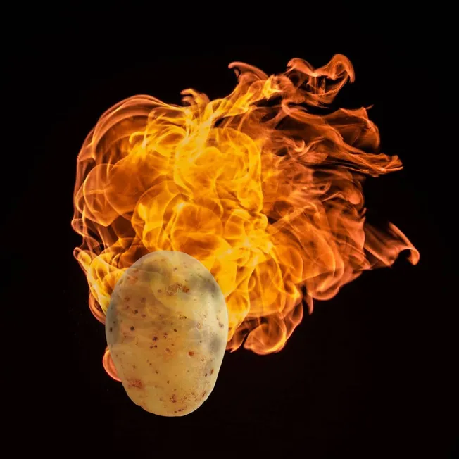 Burning potato on fire with intense flames, dramatic fiery explosion, heat, urgency, destruction, food safety, kitchen accide