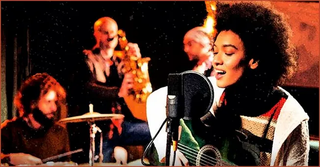 Vibrant live music performance featuring a female singer with Afro hairstyle and a band playing guitars, drums, and saxophone