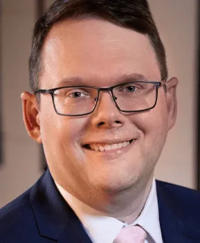 Professional businessman in glasses and suit smiling, representing music industry expert or executive for Hypebot, a leading