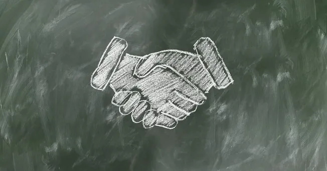 Handshake agreement symbol chalk drawing on blackboard, business partnership or collaboration concept, teamwork, trust, negot