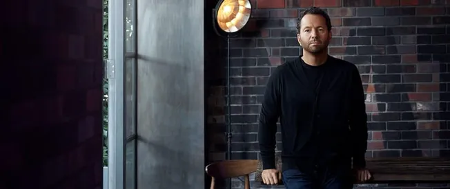 Professional musician artist in black casual clothing sitting in studio with brick wall background, preparing for music produ