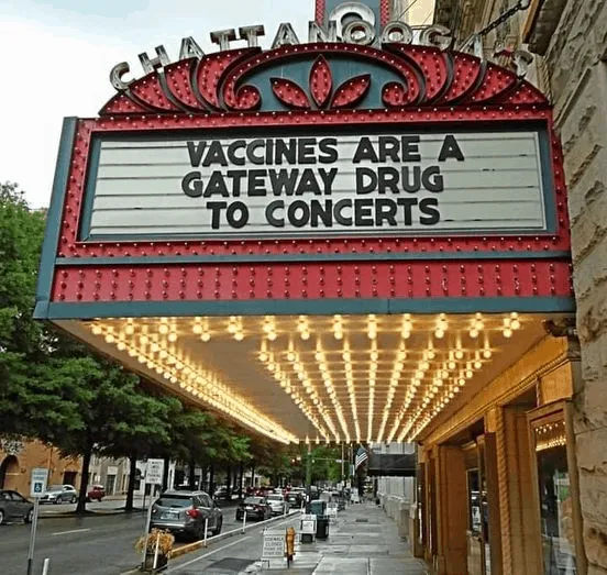 Vaccines are a gateway drug to concerts message displayed on a vintage theater marquee, highlighting health policy debates an