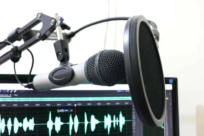 Microphone with pop filter recording audio in a studio for music or podcast production.