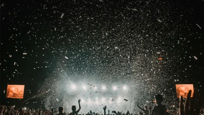 Colorful concert crowd celebrating with confetti at night, vibrant music event, lively atmosphere, music festival, concert, a