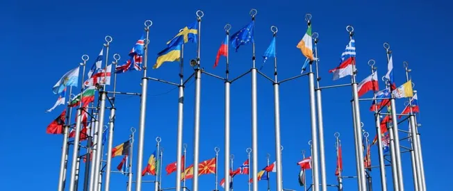 Colorful international flags flying against a bright blue sky, representing global music markets, multicultural collaboration