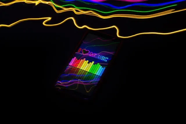 Colorful LED music equalizer display on smartphone illuminated in dark background for digital music streaming and entertainme