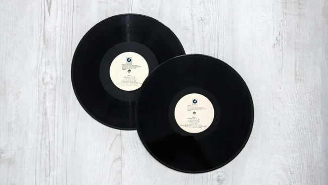 Vintage black vinyl records on a light wooden surface, ideal for music collectibles and retro music themes.