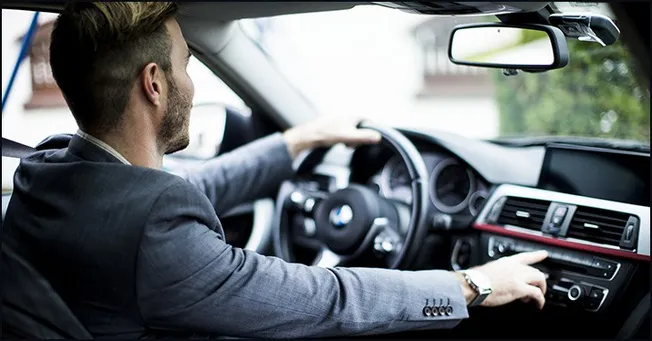 Driving a modern luxury car with a focus on in-car technology and interior design, showcasing an executive traveling or commu