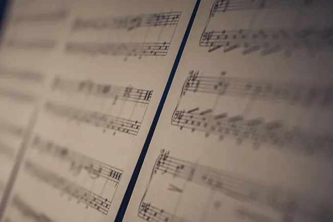 Vintage sheet music with musical notes and notation, close-up view, for music industry articles, music trends, and digital mu
