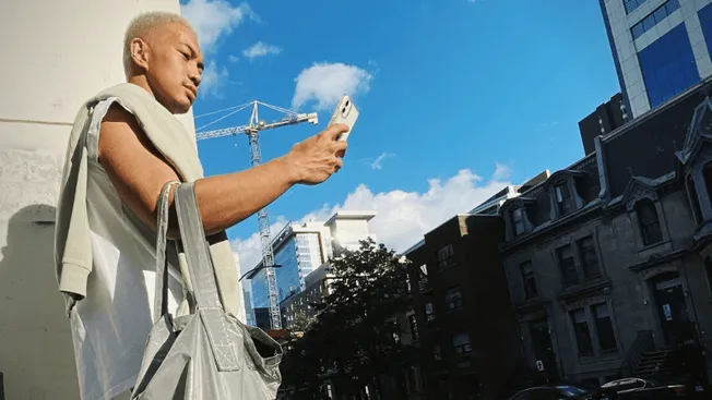 Hypebot urban young man taking selfie with cityscape background, construction crane and high-rise buildings, trending music i