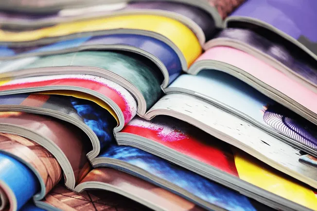 Magazine pages stacked with colorful printed images and graphics, creative layout, visual design, artistic magazine printing,