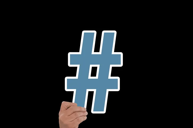 Hashtag symbol held by a hand on black background for social media and marketing SEO.
