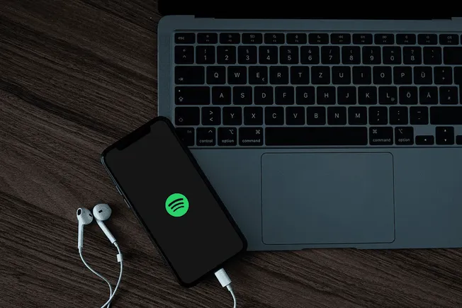 Wireless Spotify streaming on laptop and smartphone for music enthusiasts and digital marketing professionals.