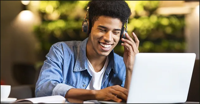 Young man enjoying music with headphones and laptop at a cafe, digital music, streaming, online entertainment, modern technol