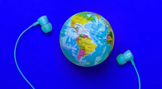 A globe with a colorful world map and a pair of blue earphones on a vibrant blue background, symbolizing global music, digita