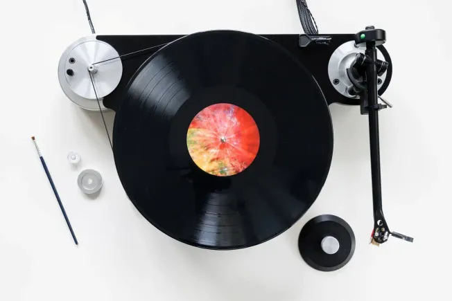 Vinyard turntable with a colorful galaxy-themed record, DJ needle arm, and cleaning brush on a white background for music pro