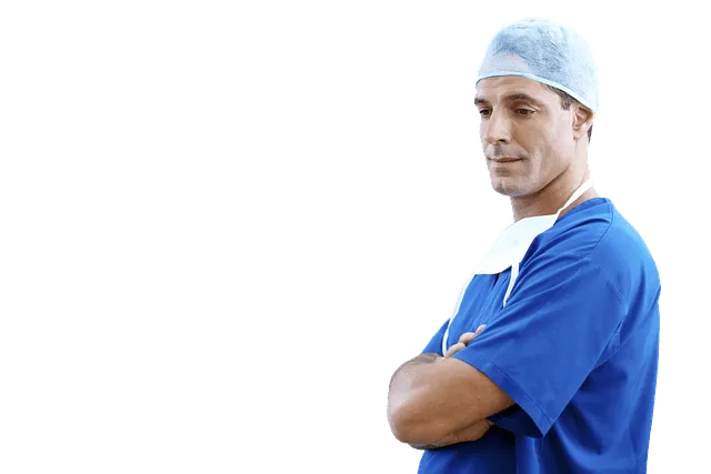 Surgical doctor wearing blue scrubs and a surgical cap, standing with arms crossed, prepared for medical procedure.
