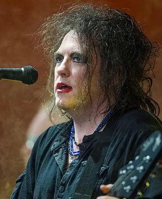A Rock musician with wild, messy hair performing on stage with intense expression and vibrant lighting.
