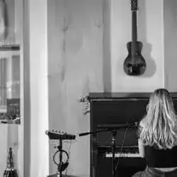 Creative musician practicing piano in a modern room with guitar hanging on the wall, capturing a relaxed music studio vibe, i