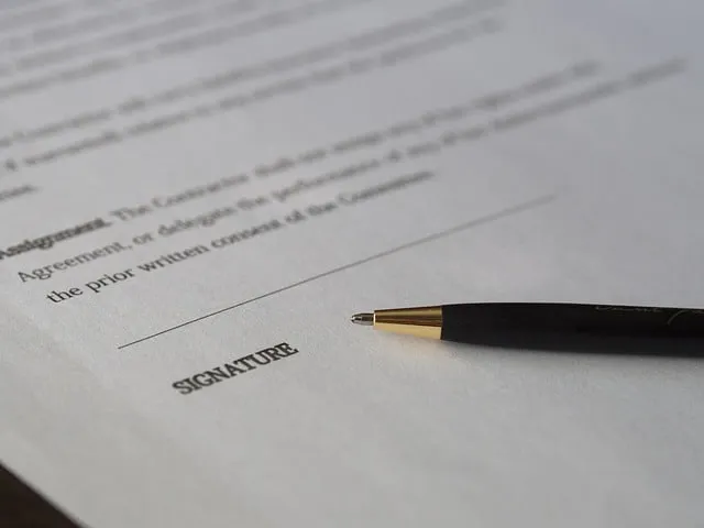 Signature on legal document with pen, close-up of paperwork for business or legal signing processes.