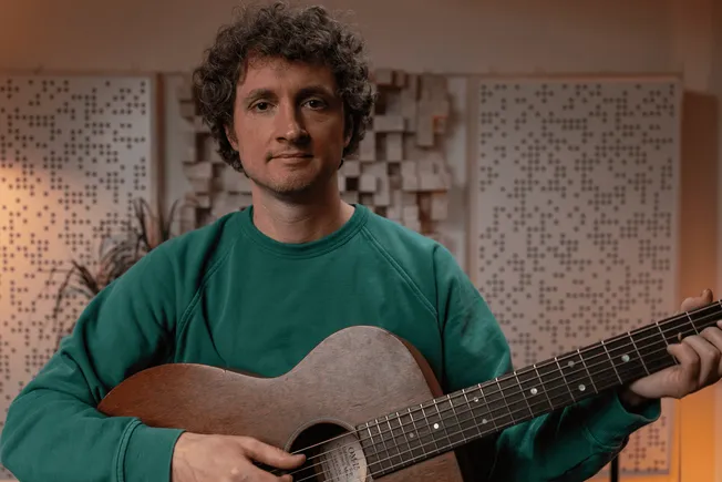 Guitar player in a recording studio, holding an acoustic guitar, working on music production, acoustic soundproofing panels o