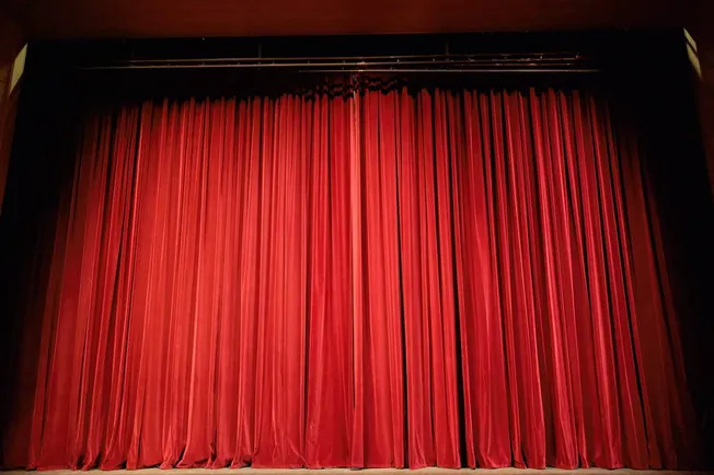 Red theater stage curtain with theater rigging and stage trim.