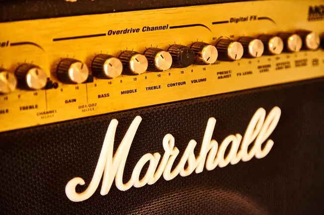 Marshall amplifier with sound control knobs and gold-colored audio equipment in close-up shot, emphasizing music production a