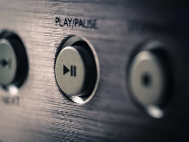 Button on audio equipment for play and pause functions, close-up shot.
