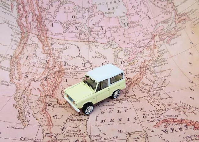 High-quality miniature car model on vintage map, travel inspiration, car travel, exploration, adventure, world map background
