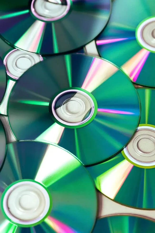 CDs and DVDs with reflective, iridescent surfaces showcasing vibrant rainbow colors, used in music, movies, and data storage.