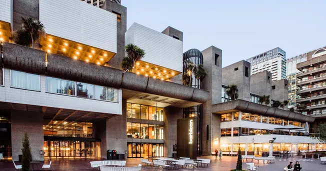 Modern urban building with glass windows, outdoor seating, and warm lighting, highlighting architecture and cityscape, perfec