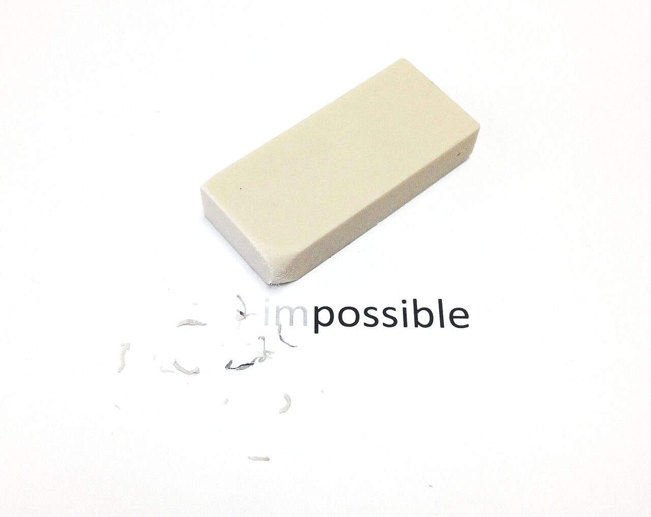 Plain white eraser on a white background with the word "impossible" printed beneath, with part of the "i" erased.