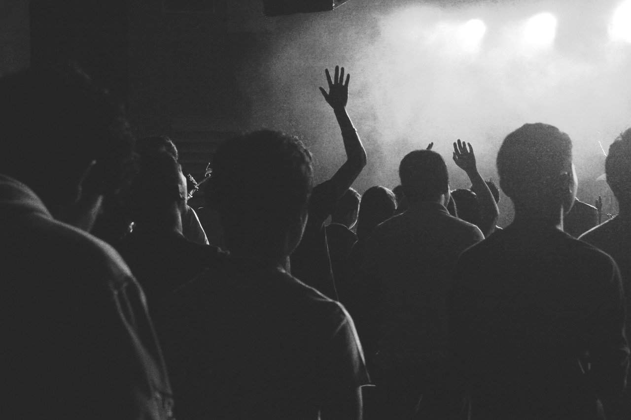 Crowd at a music concert or live event, raising hands and enjoying the show, black and white photo, energetic audience experience, entertainment, nightlife, event photography, Hypebot.