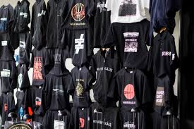 Black hoodies and jackets featuring various graphic designs displayed at a merchandise store.