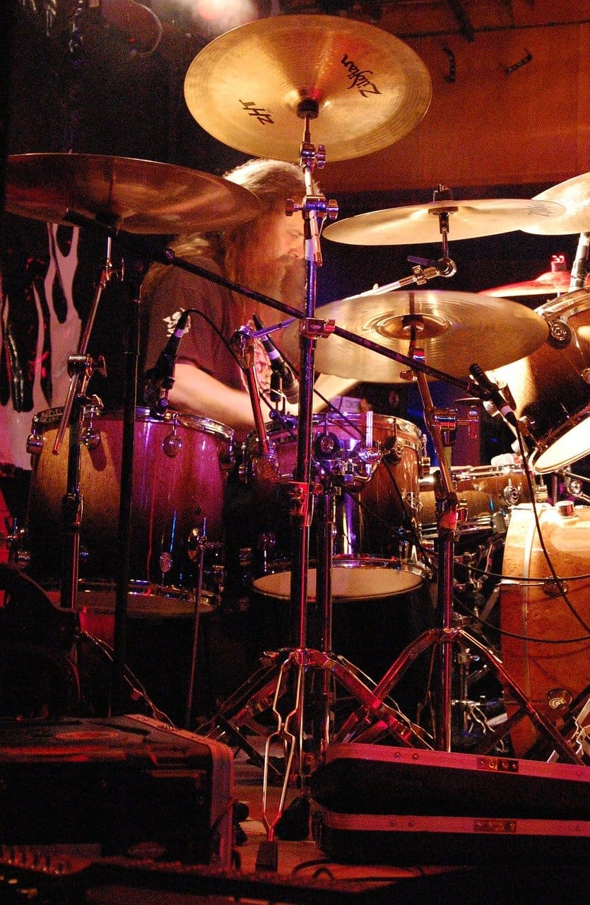 DRUMMER performing live on stage with multiple cymbals and drums, vibrant stage lighting, jazz and music performance, musical artist, live concert, Hypebot music news.