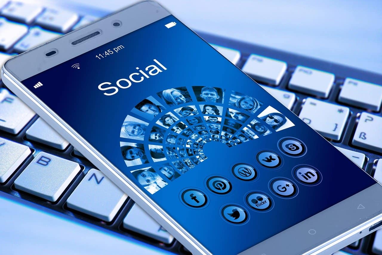Social media smartphone with various app icons and user profile images on the screen.