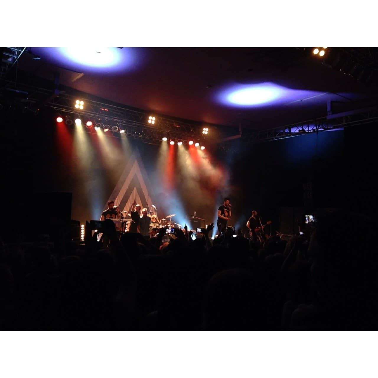 Vibrant live concert scene with band performing on stage under colorful lights, engaging audience with music, showcasing modern event production, and emphasizing entertainment and live music experience.