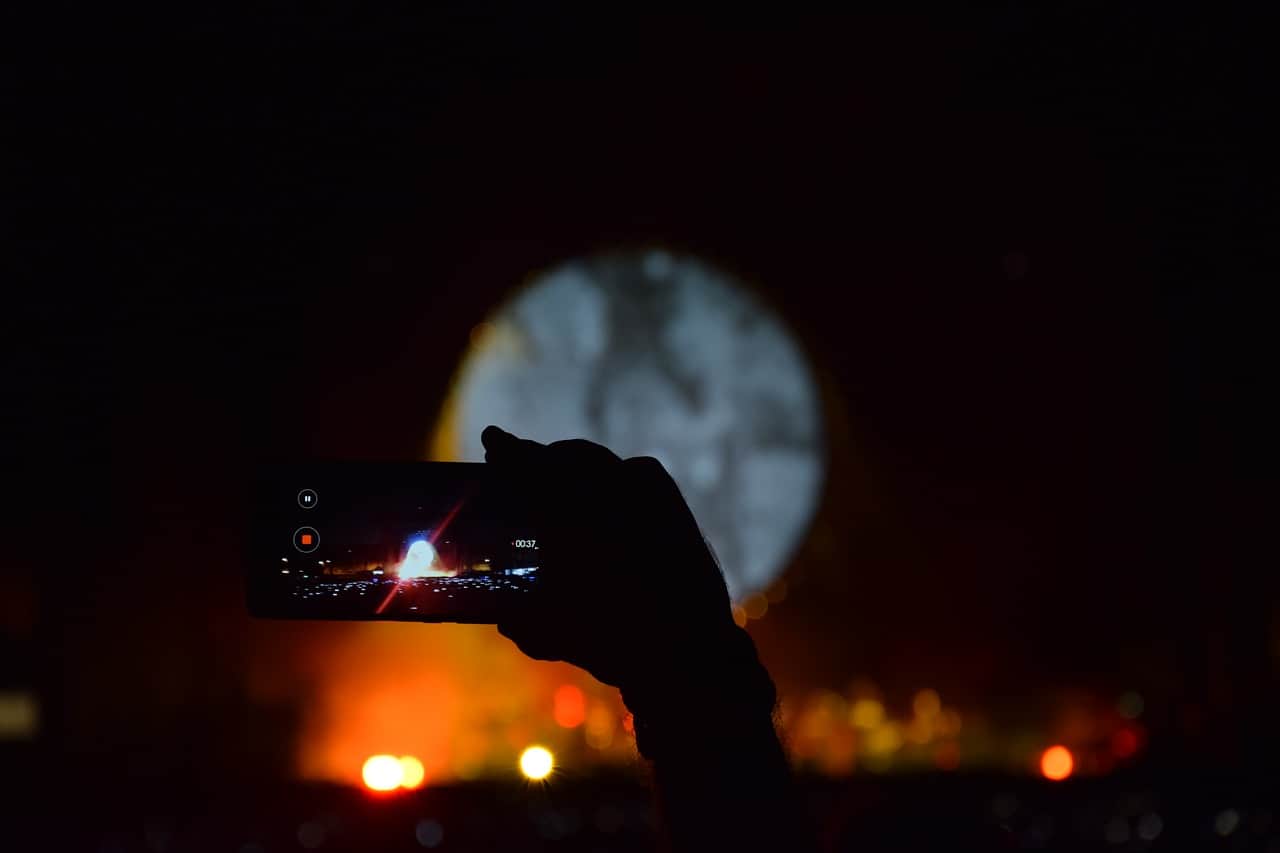 Recording a video of a fireworks display using a smartphone during nighttime.