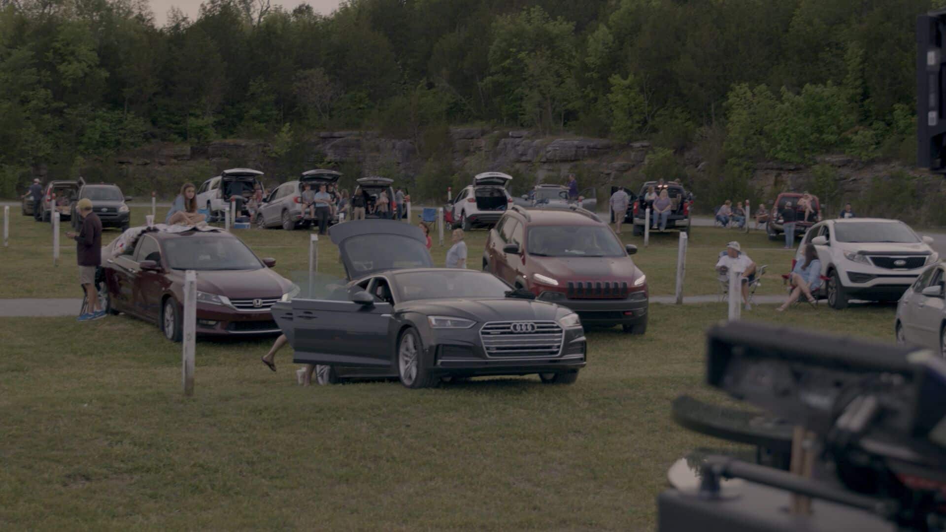 Audi convertible with open hood at outdoor car meetup event.